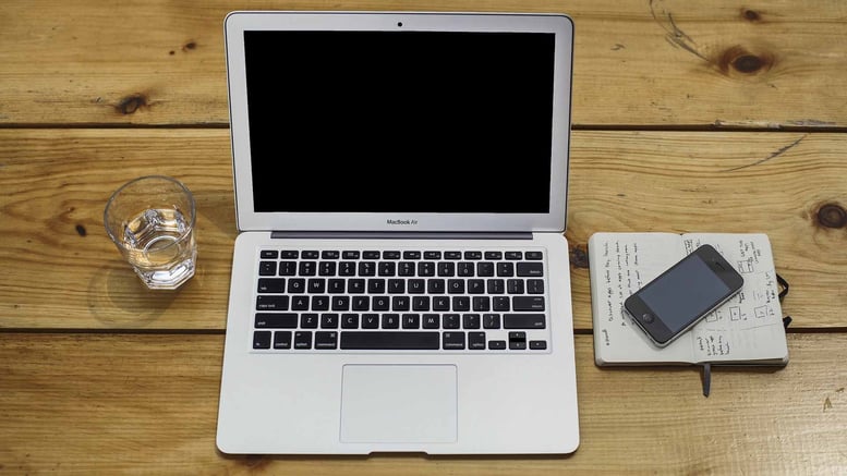 Laptop and mobile phone on a wooden desk